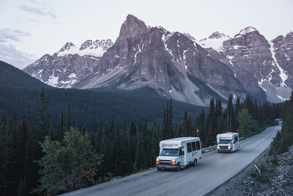 Two white shuttle buses on a mountain road